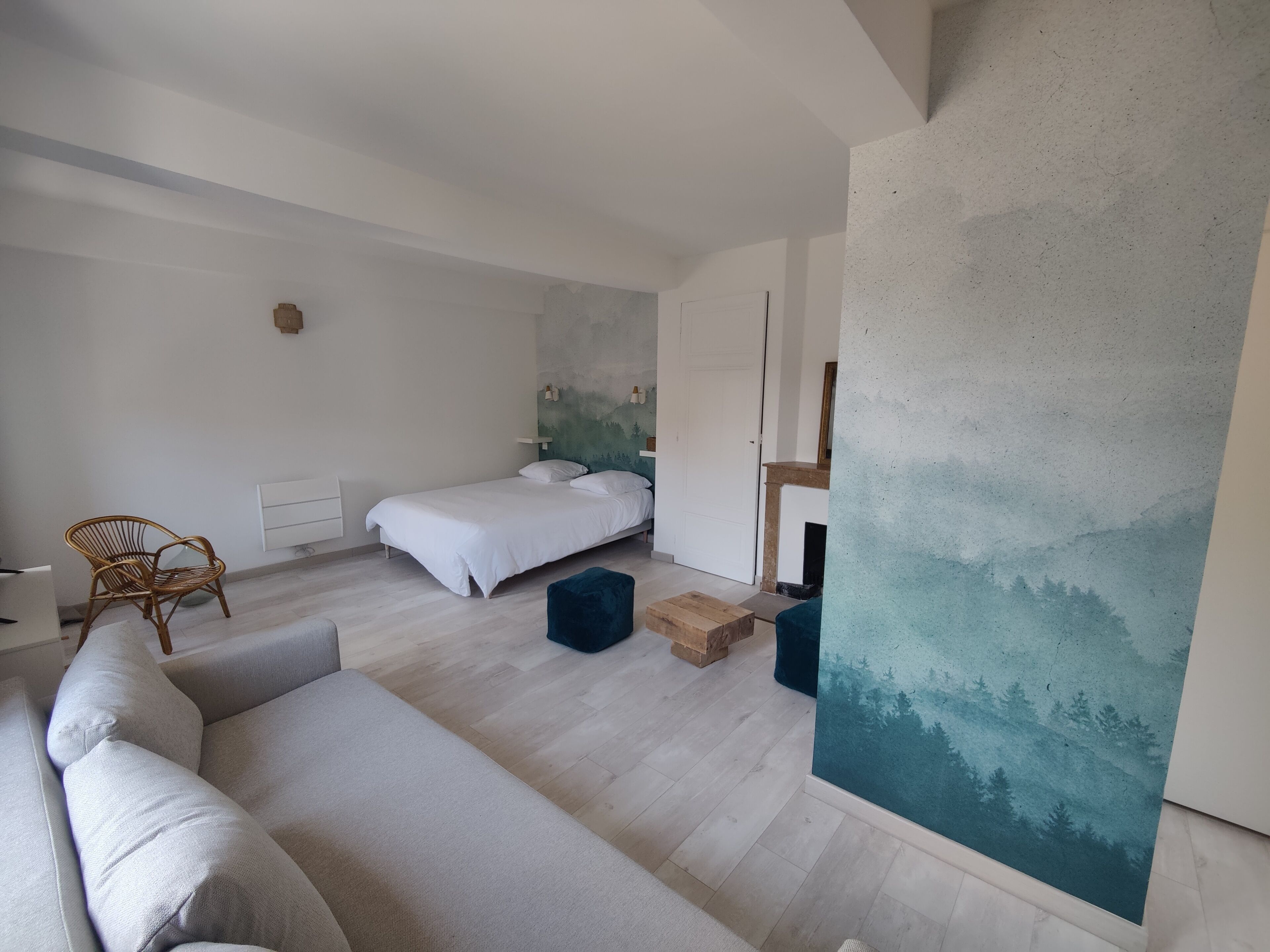 Une chambre à coucher moderne avec un lit, un canapé, un fauteuil et un tableau au mur.