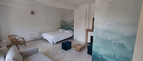 Un dormitorio moderno con cama, sofá, silla y un cuadro en la pared.