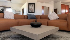 Un salon moderne avec un canapé d’angle, une table basse et un tableau encadré au mur.