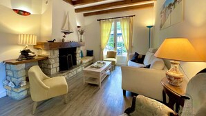 Un salón acogedor con chimenea de piedra, vigas de madera, un sofá y una mesa de centro.