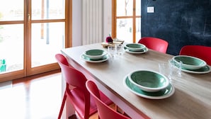 A dining area with a wooden table, red chairs, and green plates. - Cave 47 Zona Ospedale Giovanni Xxiii (Bergamo)