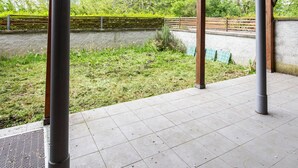 A covered outdoor area with a pergola structure, a paved walkway, and a grassy area with trees in the background. - Cave 47 Zona Ospedale Giovanni Xxiii (Bergamo)