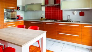 A modern kitchen with wooden cabinets, a stainless steel range, and red accents. - Cave 47 Zona Ospedale Giovanni Xxiii (Bergamo)