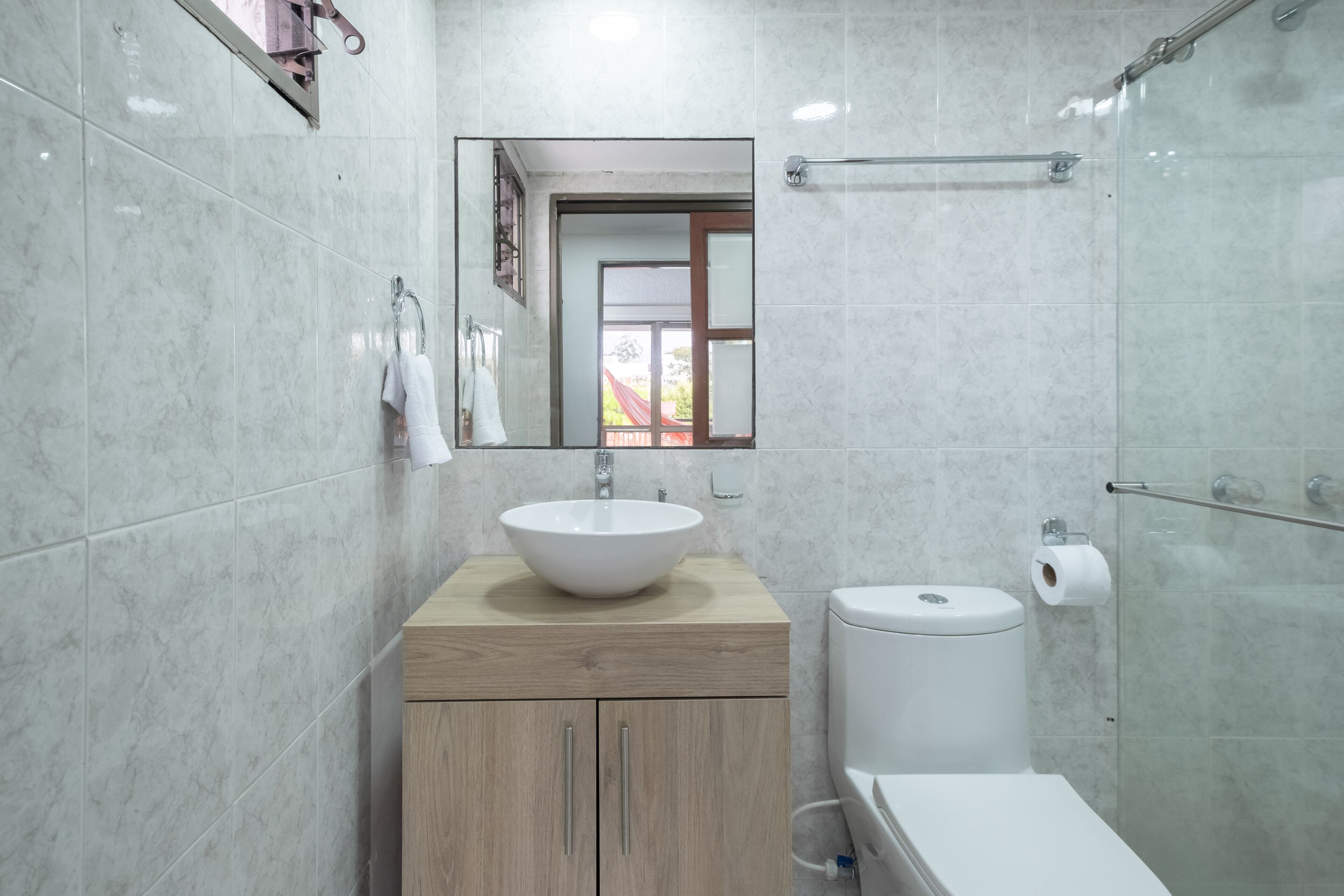 A modern bathroom with a large sink, wooden vanity, toilet, and a glass shower enclosure.