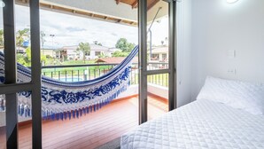 A bedroom with a bed, a hammock, and a balcony with a view of houses and greenery. - Hotel Chalet La Sofia by Majuva (Armenia)