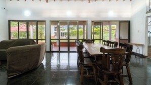 A spacious room with a wooden ceiling, a large dining table with chairs, a covered sofa, and large sliding glass doors leading to an outdoor patio. - Hotel Chalet La Sofia by Majuva (Armenia)