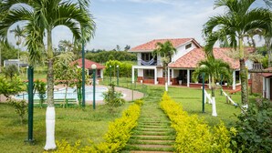 A large house with a red-tiled roof, surrounded by lush greenery and palm trees. - Hotel Chalet La Sofia by Majuva (Armenia)