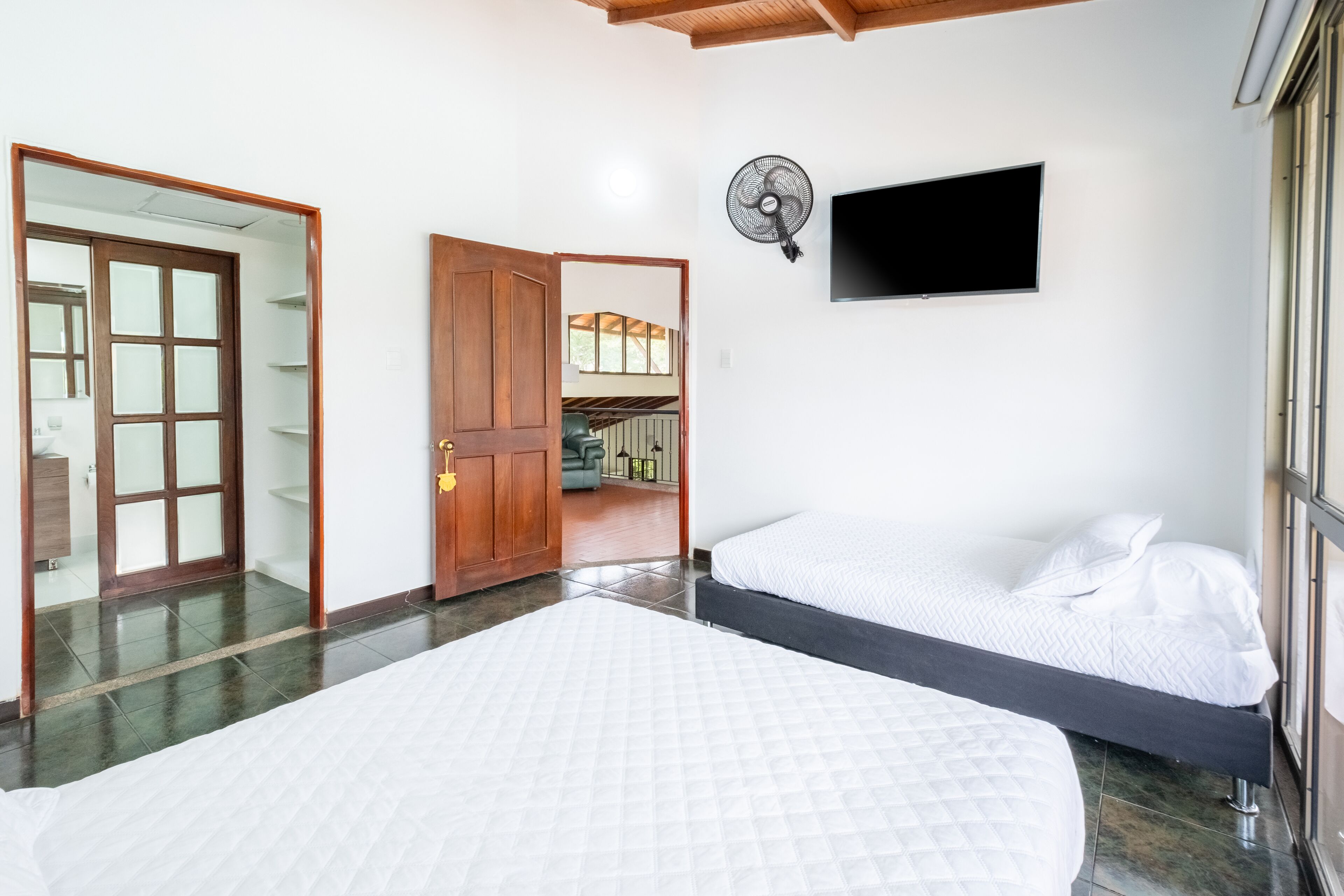 A bedroom with a bed, a TV, and a fan.