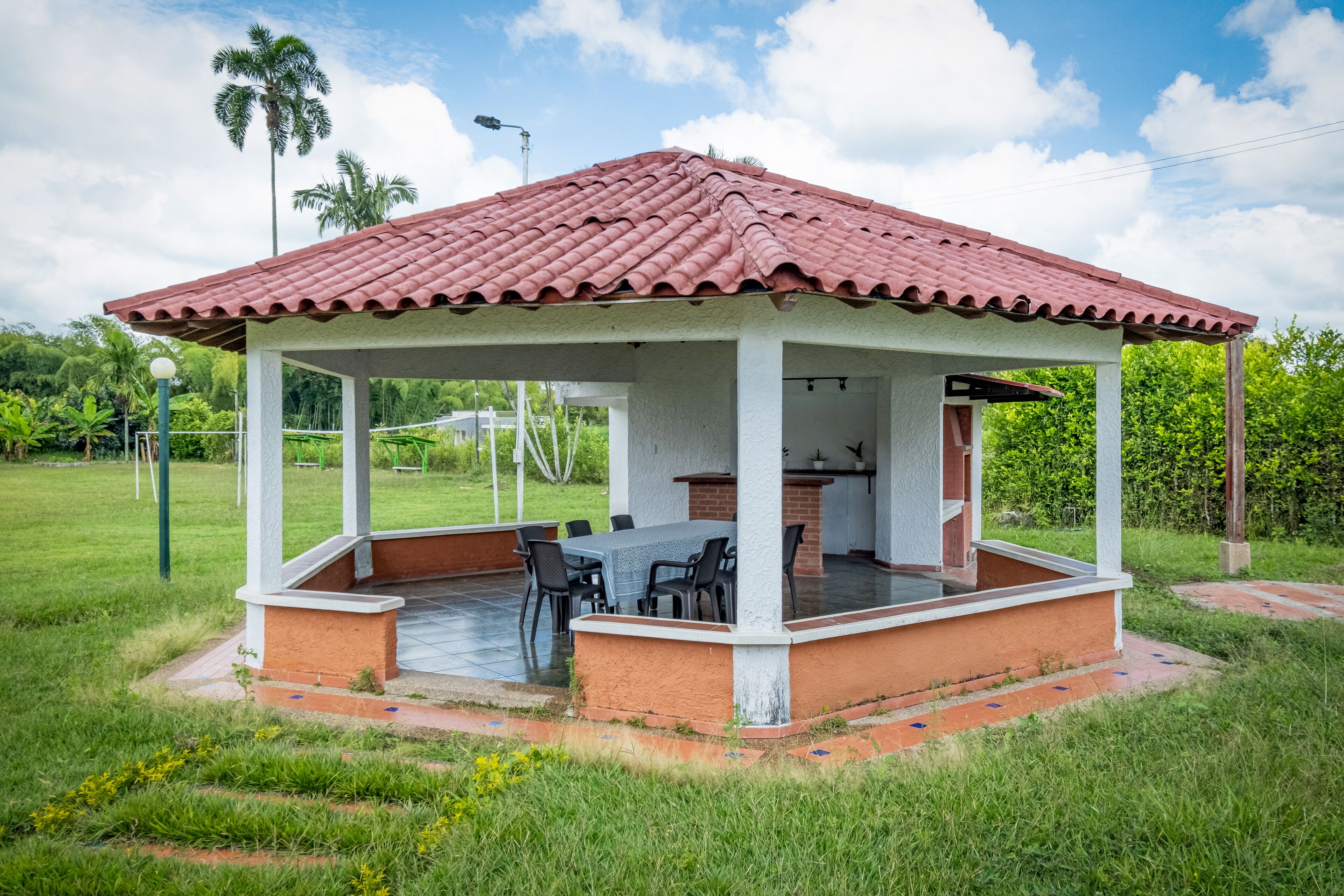 Un espacio al aire libre cubierto con techo de baldosas, una mesa y sillas.