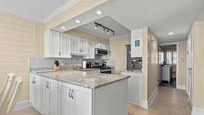 A modern kitchen with white cabinets, a granite countertop, and a large island. - Crescent Sands of WH-H2 3Br OF Condo (North Myrtle Beach)