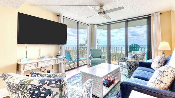 A spacious living room with a flat-screen TV, a ceiling fan, and a large window offering a view of the ocean. - Crescent Sands of WH-H2 3Br OF Condo (North Myrtle Beach)