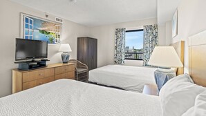 Une chambre d’hôtel avec deux lits, une télévision, un bureau et une fenêtre avec des rideaux.