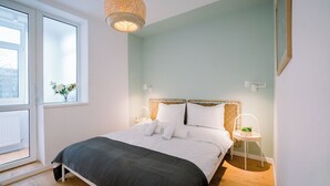 Una camera da letto con un letto, una finestra, un lampadario e un comodino con una pianta.