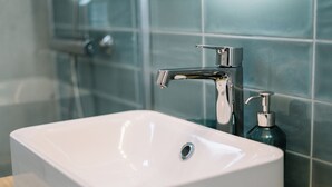 Un bagno con lavandino bianco, rubinetteria cromata e dispenser per sapone.