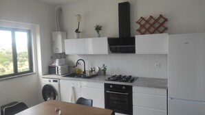 A modern kitchen with a washing machine, a stove, a sink, and a refrigerator.