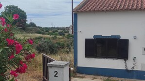 A building with a tiled roof, a window with black shutters, and a mailbox marked with the number 2.