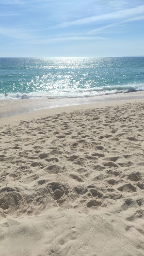 Une plage de sable où l’on peut voir des empreintes menant à l’eau.