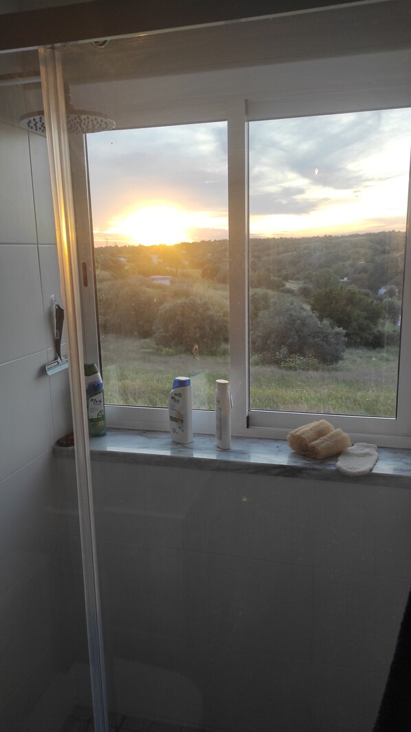 Une fenêtre de cuisine donnant sur un paysage boisé, avec une vue sur le coucher du soleil.