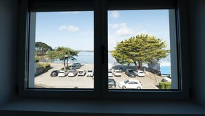 Vista a través de una ventana que muestra un estacionamiento con coches y un árbol en primer plano.