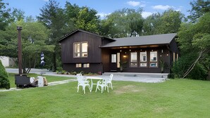 A modern building with a dark exterior, a flat roof, and a small porch area with white chairs. - Doran Farm & Wedding Venue (Richmond Hill)