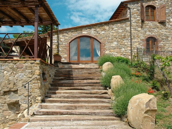 A stone building with a wooden staircase leading to a large arched doorway.
