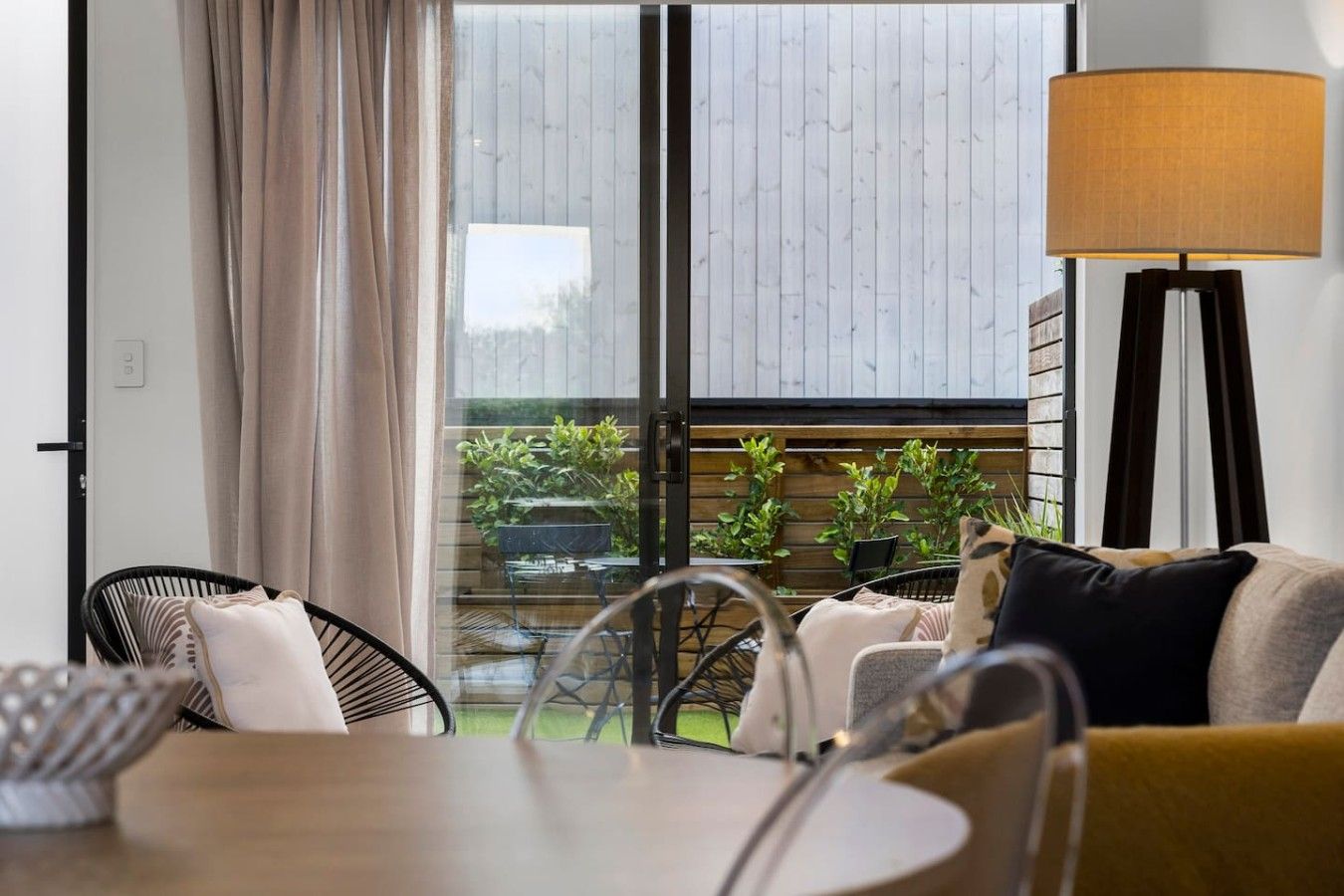 A modern living room with a sofa, chairs, a table, and a floor lamp.