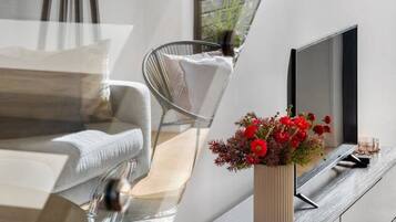 A modern interior with a dining area, a sofa, a chair, a TV, and a plant.
