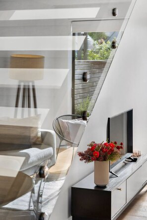 Ein modernes Interieur mit Essbereich, einer Couch, einem Sessel, einem Fernseher und einer Pflanze.