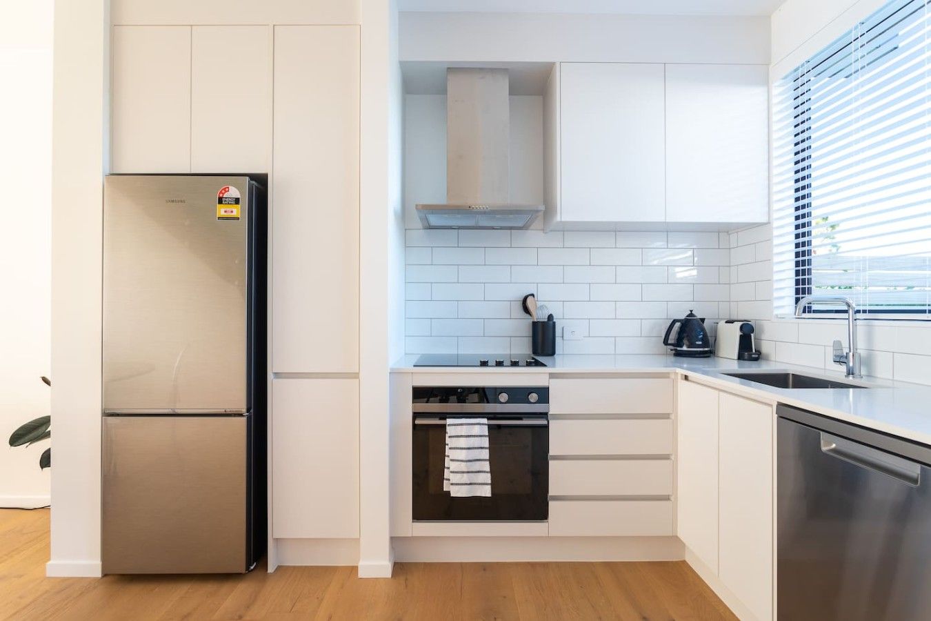 A compact kitchen with a stainless steel refrigerator, a built-in oven, and a dishwasher.