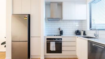 A compact kitchen with a stainless steel refrigerator, a built-in oven, and a dishwasher.