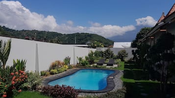 Relax by the serene pool surrounded by lush greenery and a well-maintained lawn.