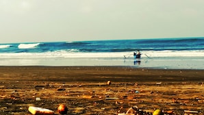 Una playa con basura y un bote en el agua.
