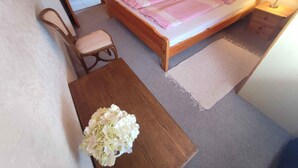 A small, cozy bedroom with a wooden bed, two bedside lamps, a chair, and a small table with a vase of flowers. - Holiday apartment with pool, Wi-Fi and terrace (Siófok)