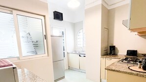 Una cocina con encimera de granito, refrigerador, estufa y cafetera.