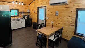 L’intérieur d’une cabine est aménagé avec des éléments en bois, comprend un coin cuisine, une table à manger avec des chaises et un appareil de climatisation.