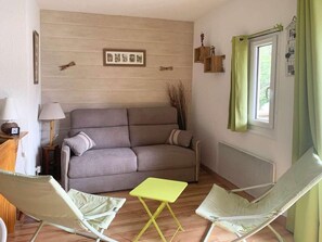 A living room with a sofa, two armchairs, a small table, a lamp, and a window with curtains.