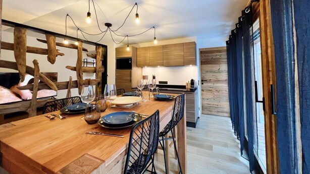 Une cuisine moderne avec des meubles en bois, un îlot central doté de tabourets de bar et un éclairage suspendu.