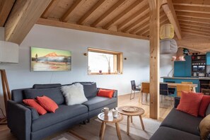 A cozy living room with a sofa, a coffee table, and a dining area with chairs and a table.