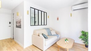 A modern living room with a beige sofa, a small wooden table, and a potted plant. - Lavie Maison Cozy Balneo Sauna (Bordeaux)
