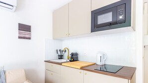 A compact kitchenette with a microwave, sink, and coffee maker.