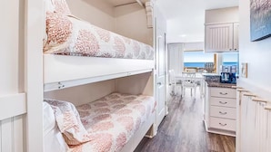 Een compacte, goed verlichte kamer met stapelbedden, een kitchenette en uitzicht op zee.