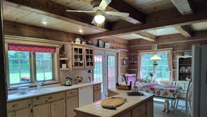 A rustic kitchen with wooden cabinets, a central island, and a dining area with a table and chairs.