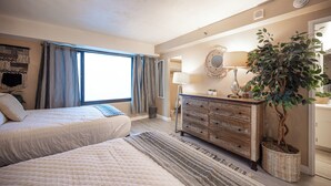 A bedroom with a bed, a dresser, a mirror, a lamp, and a potted plant. - Stay Together Suites | Strip Condote (Las Vegas)