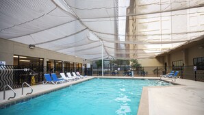 An indoor swimming pool with clear water, surrounded by lounge chairs and a covered area with a patterned wall. - Stay Together Suites | Strip Condote (Las Vegas)