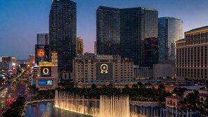 A cityscape with prominent buildings including The Cosmopolitan and The Jackle Club, a large fountain, and a casino sign. - Stay Together Suites | Strip Condote (Las Vegas)