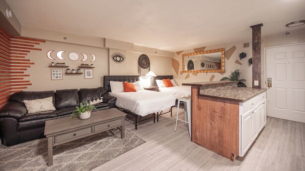 A modern living room with a sofa, two beds, a coffee table, and a kitchen area with a countertop. - Stay Together Suites | Strip Condote (Las Vegas)