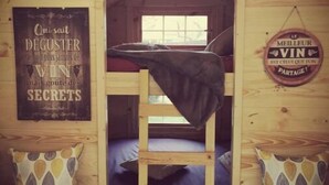 A cozy wooden cabin room with bunk beds, a small table with candles, and decorative signs on the walls. - 1 Bedroom Chalet in Pruniers-en-Sologne (Pruniers-en-Sologne)