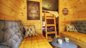 A cozy cabin interior with a bunk bed, two sofas, and a small table. - 1 Bedroom Chalet in Pruniers-en-Sologne (Pruniers-en-Sologne)