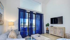 Een woonkamer met een bank, een salontafel en een aan de muur bevestigde televisie.