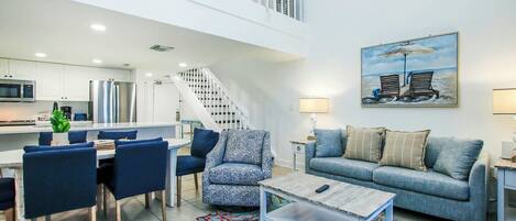 A modern living room with a dining area, a staircase, and a kitchen.